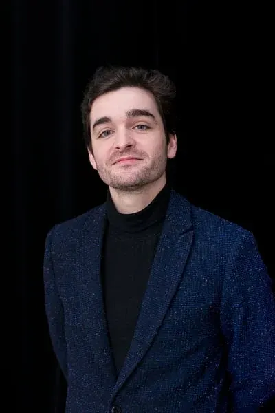 Portrait of Léo Barcet in a midnight-blue jacket against a black background