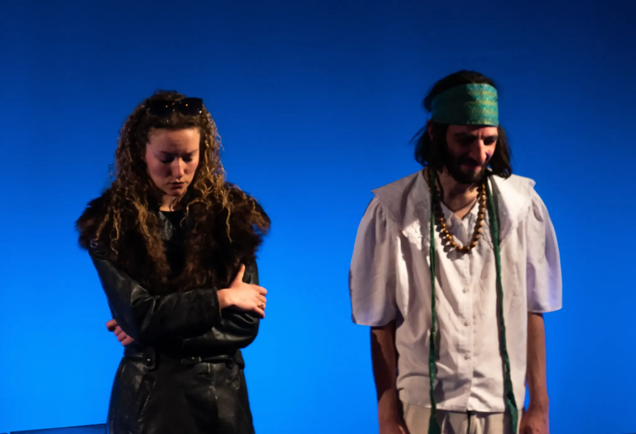 Two actors from the company on stage in blue light