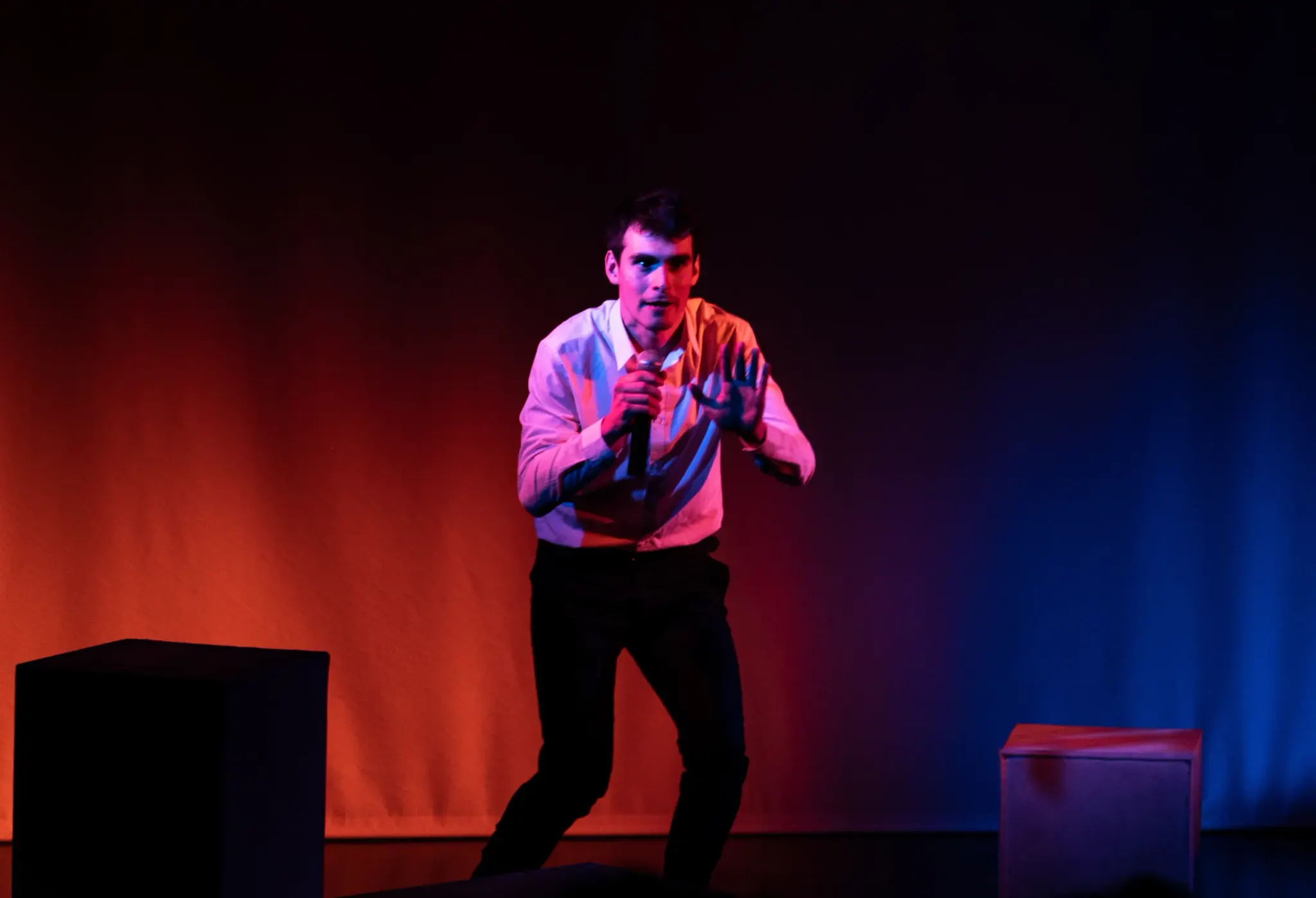 Léo Barcet on stage, microphone in hand, in orange and blue light